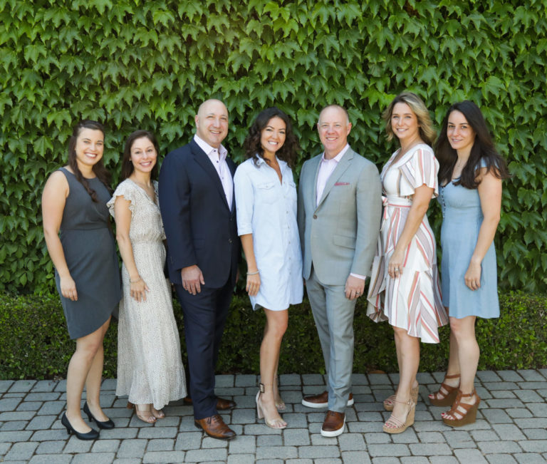 group of sales team people against green ivy wall