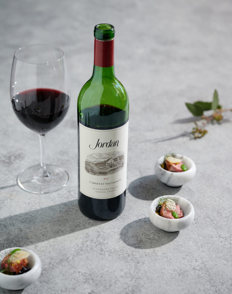 Bottle of 2017 Jordan Cabernet Sauvignon on gray board with food pairings
