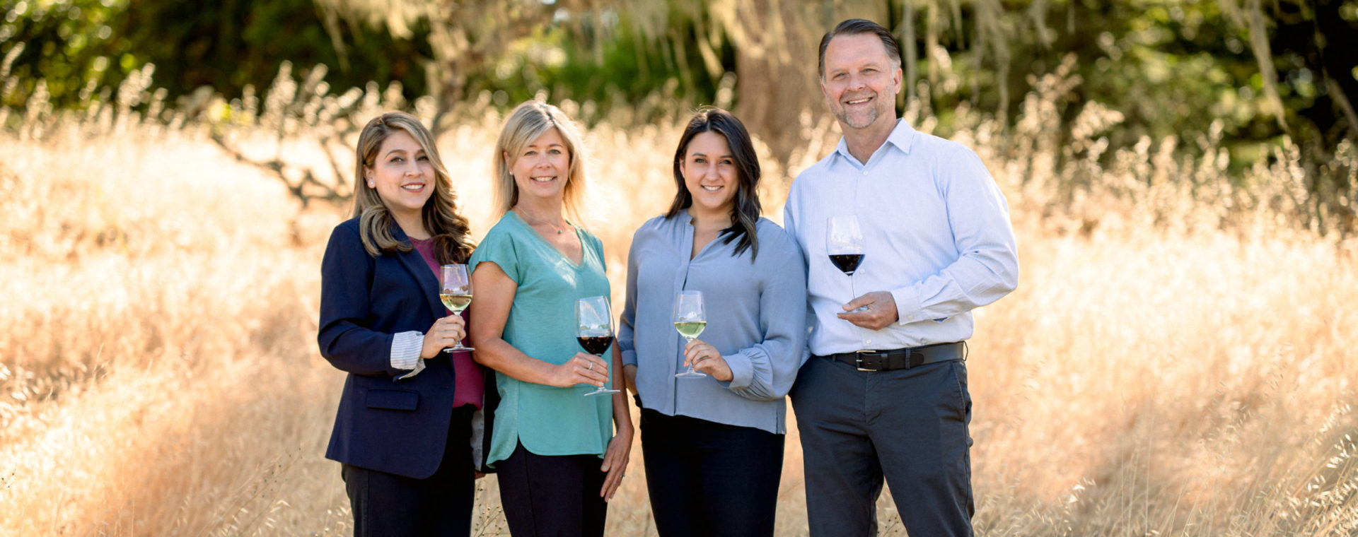 Four employees standing with glass of wine