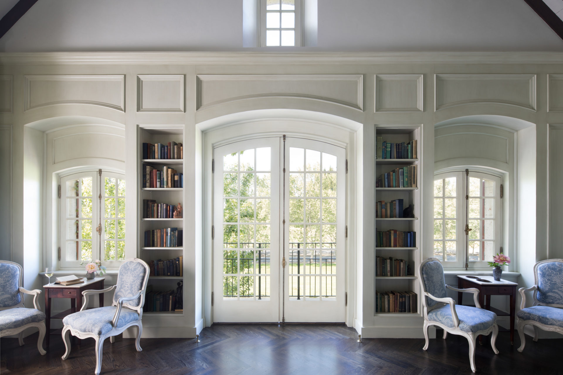 large room with bookshelves, decorative chairs and windows