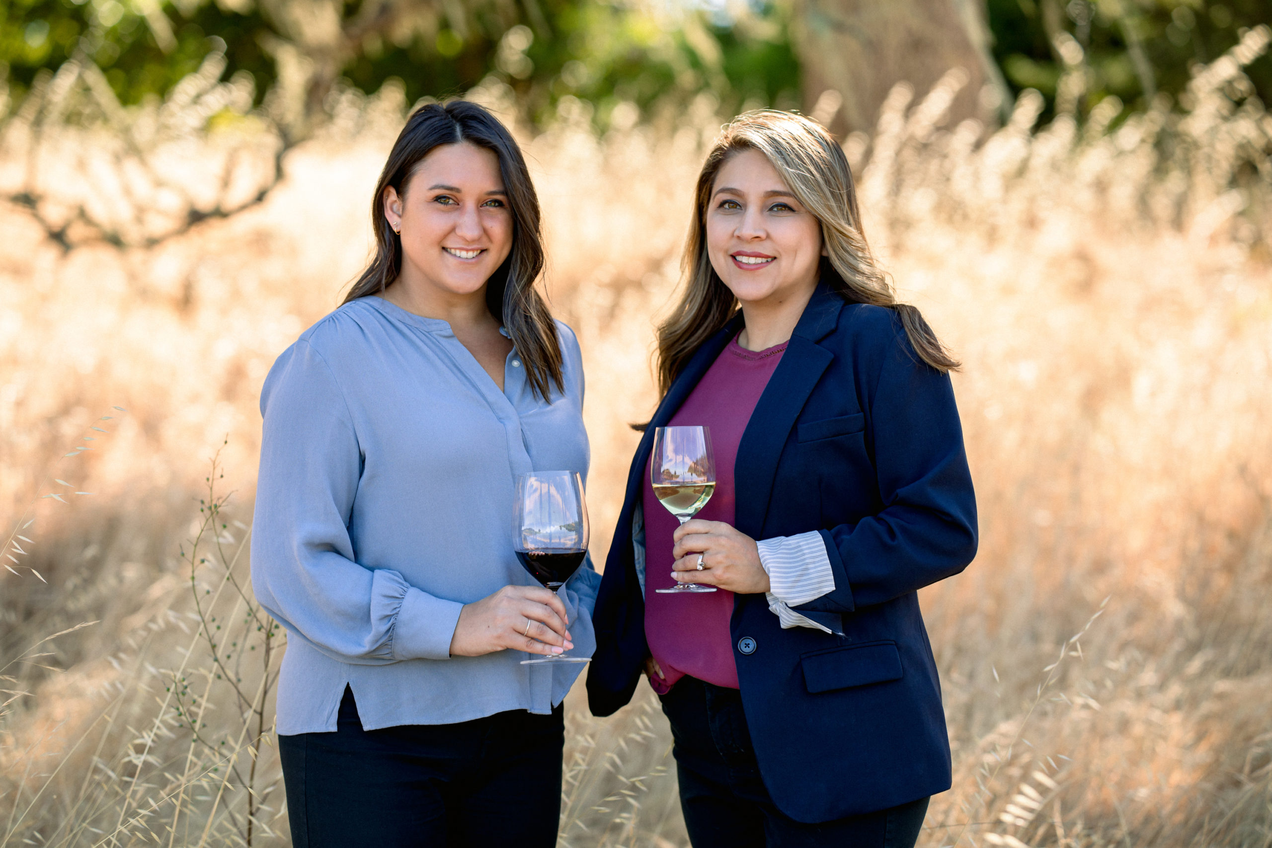 two women standing with glass of wine in business attire