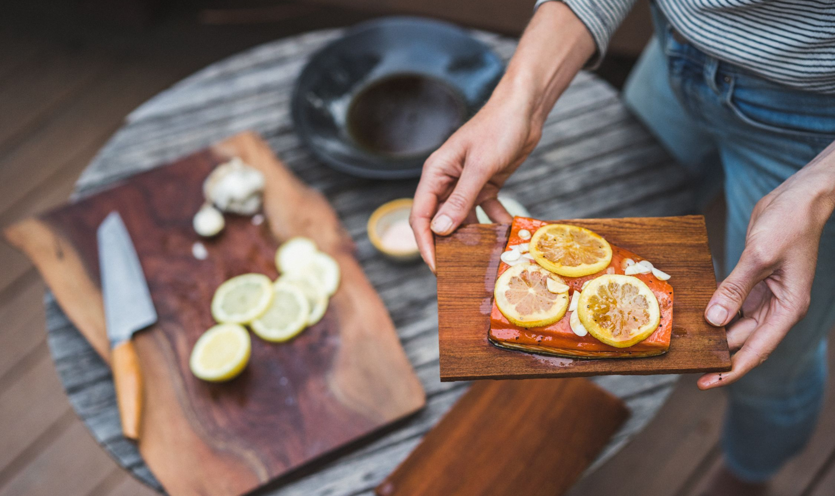 hands holding roasted salmon filet with lemon slices on top