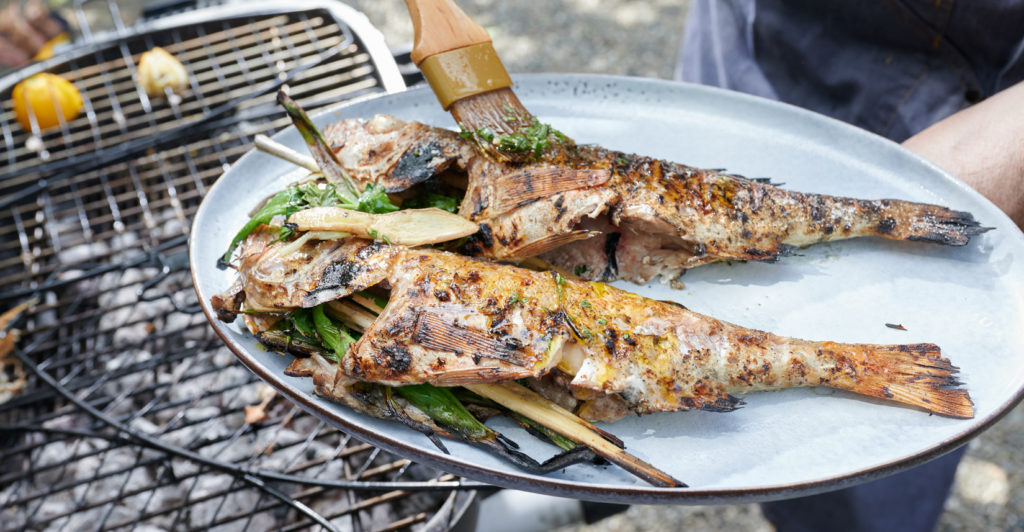 chef applying marinade with brush on two fish fillets