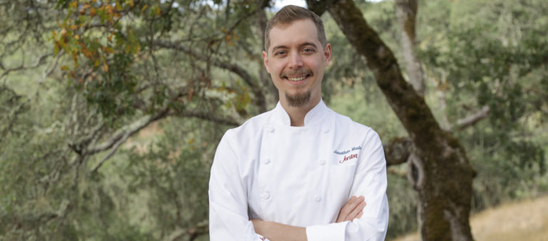 man in chef's coat standing in nature