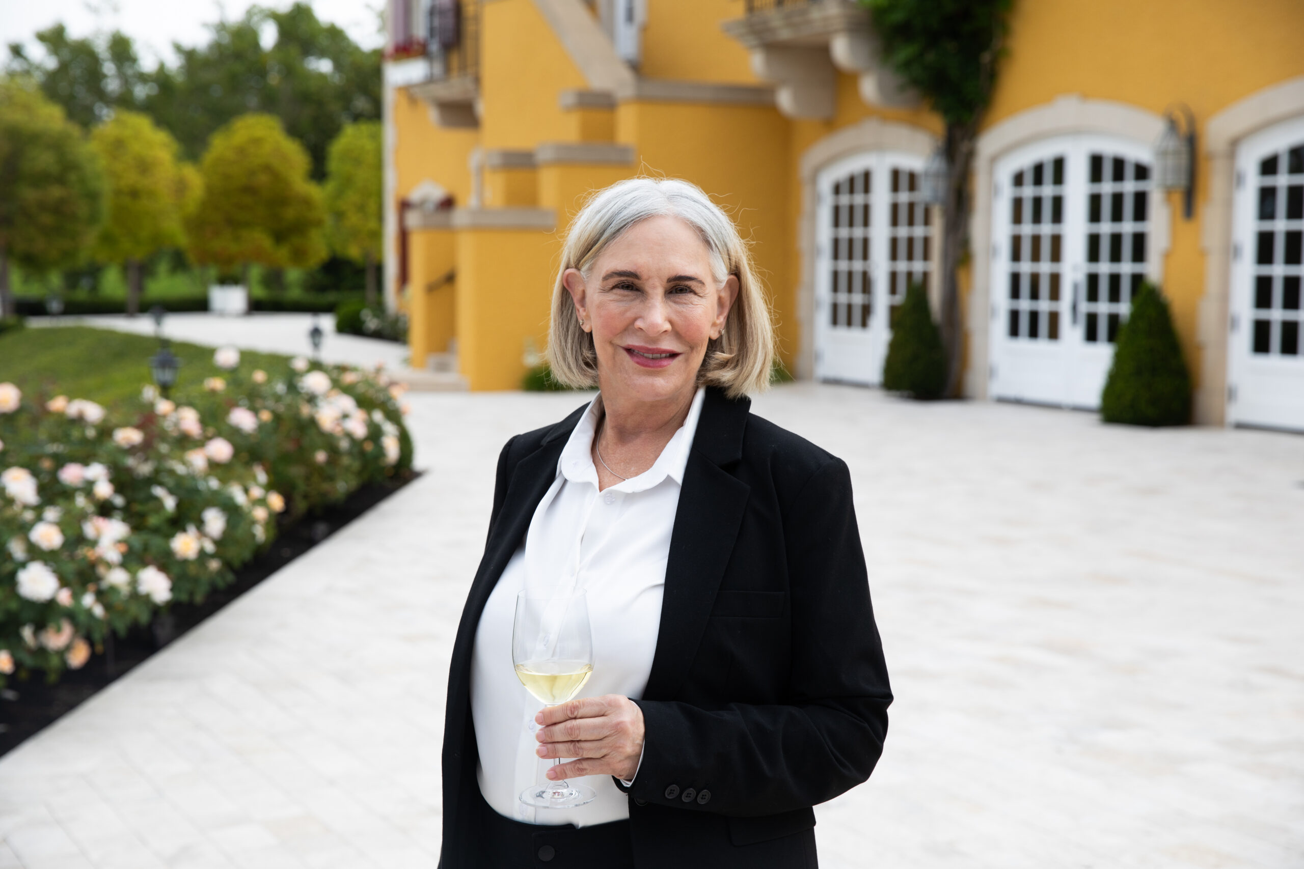 headshot of female sommelier holding glass of white wine