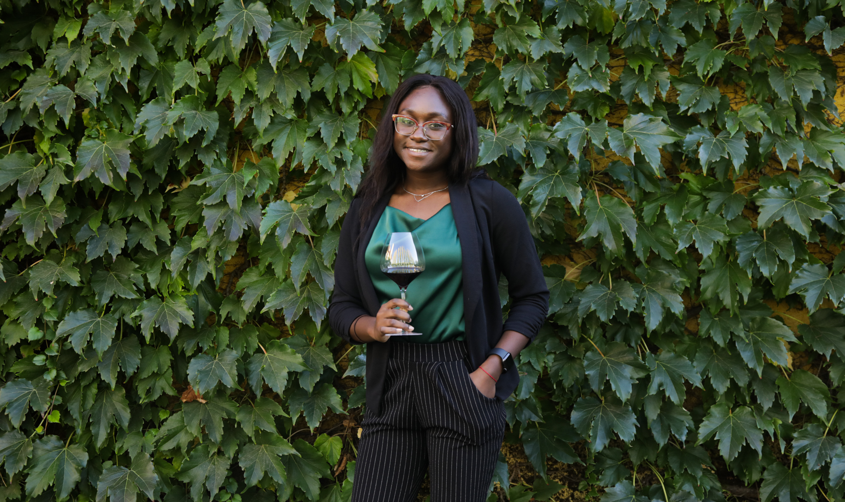 woman standing in front of ivy wall with glass of cabernet in hand