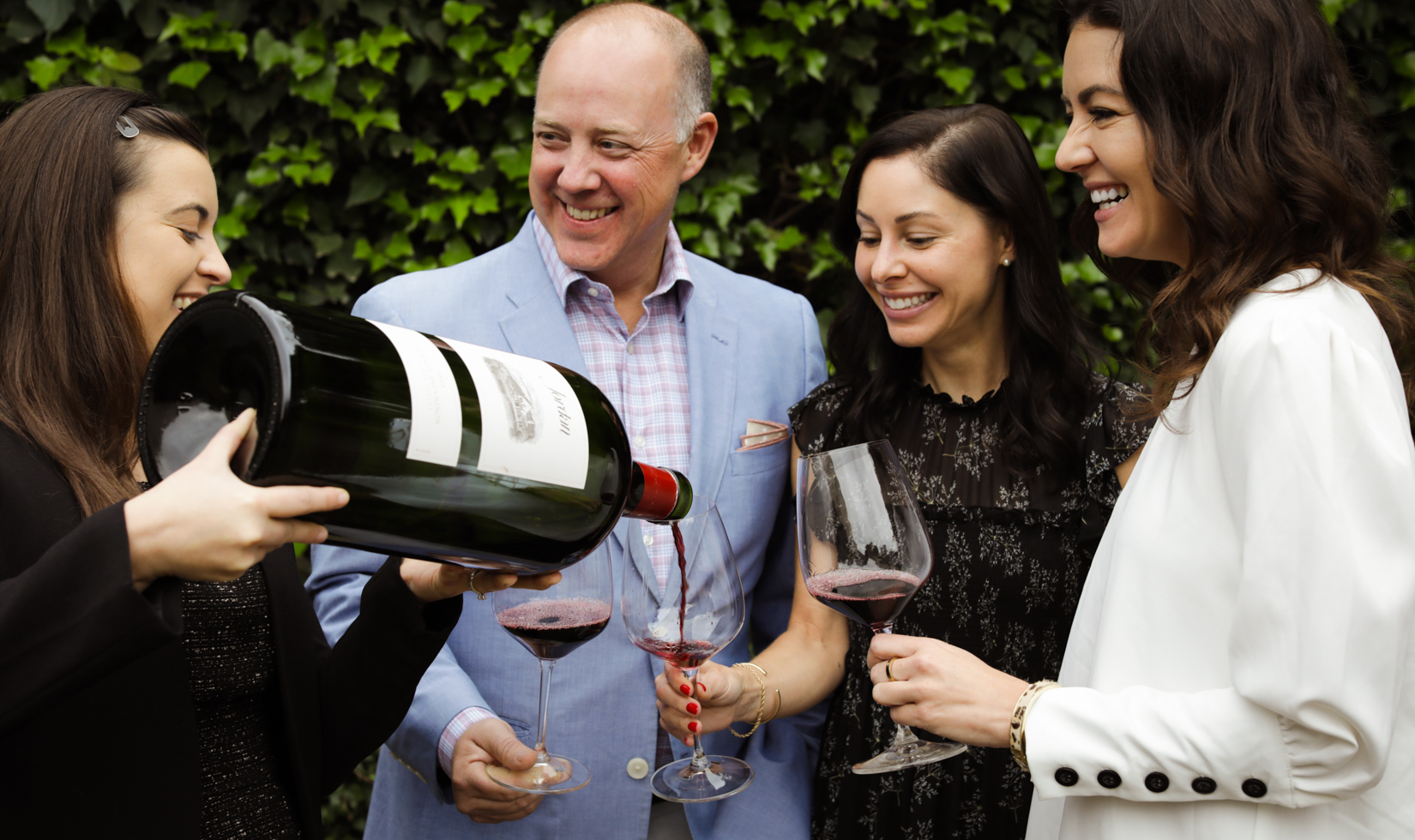 group of people laughing with wine glasses