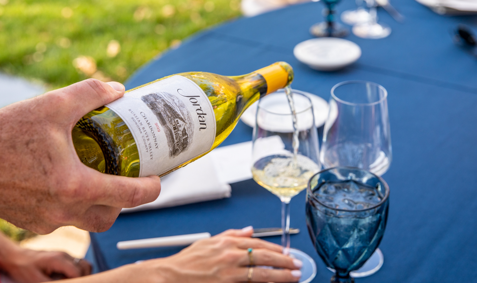 chardonnay wine pouring into wine glass at dinner table