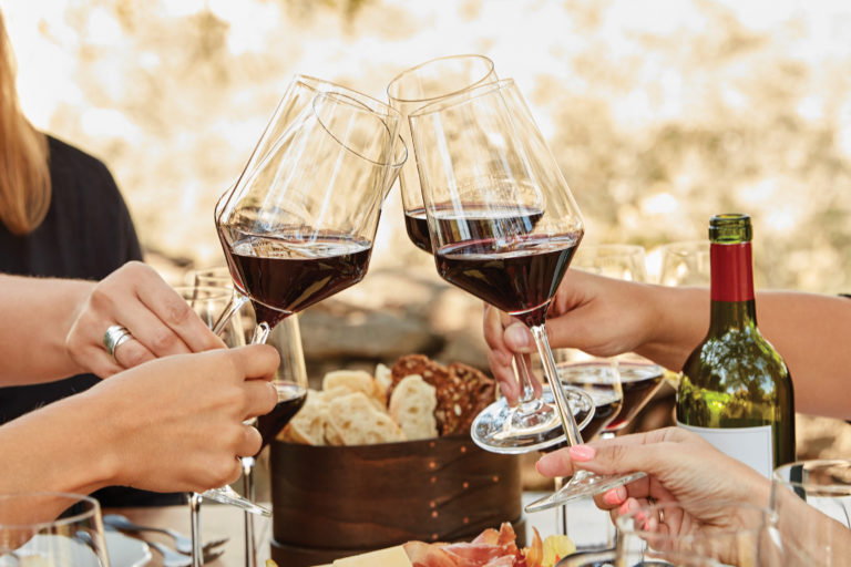 four red wine glasses toasting at lunch table