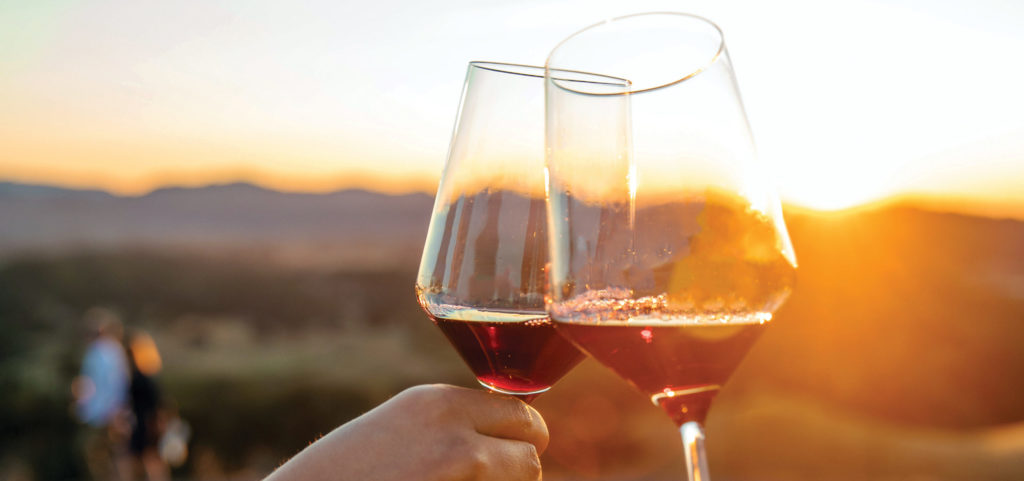 two wine glasses toasting at sunset