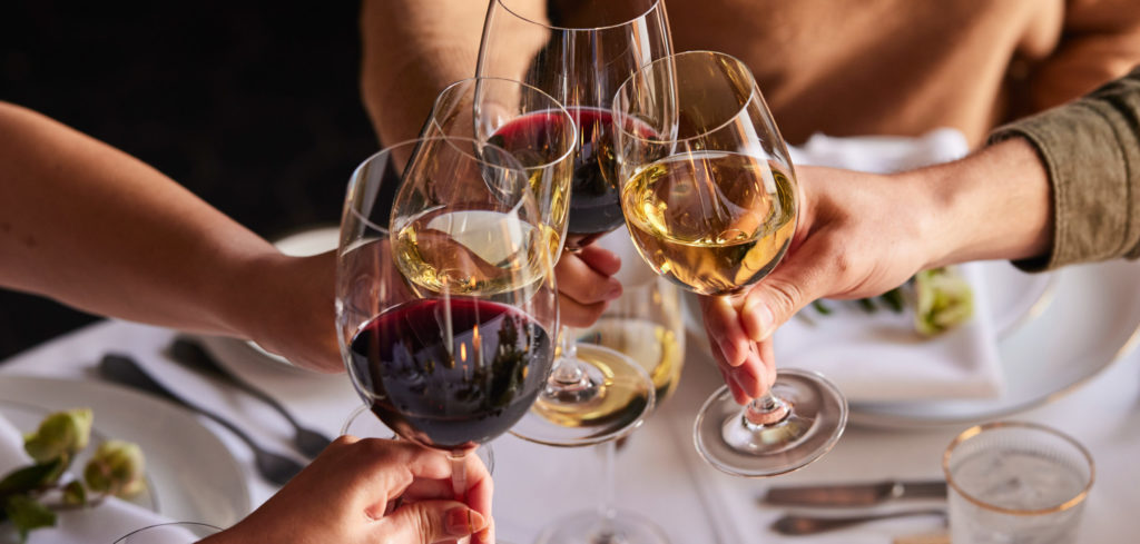 group of cabernet and chardonnay wine glasses toasting at dinner table