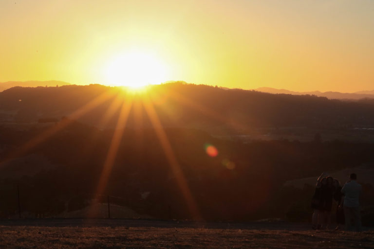 Sunset over ridge of mountain on clear day.