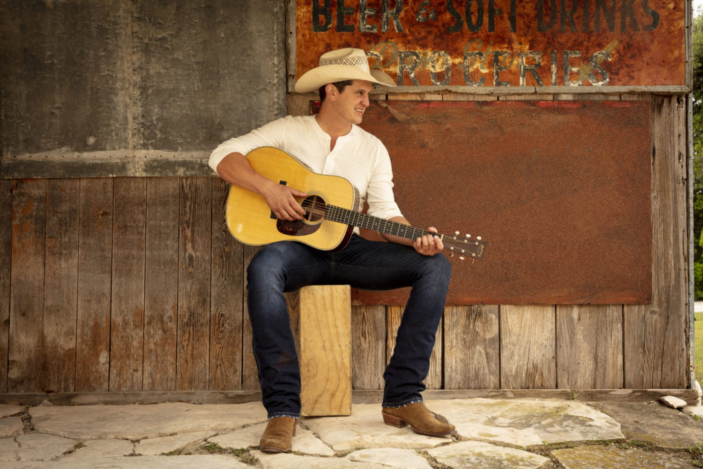 country music singer playing acoustic guitar with cowboy hat