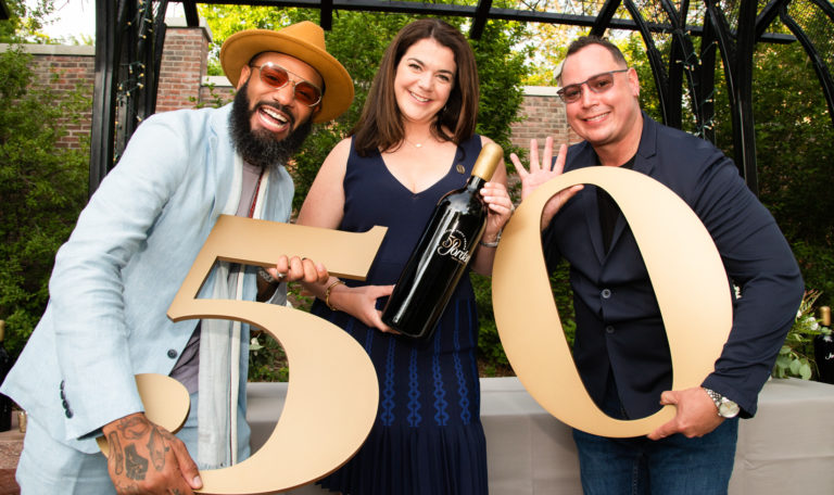 three people standing holding a 50th anniversary sign