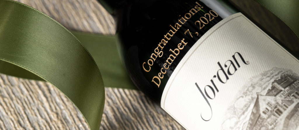 etched wine bottle laying with green ribbon