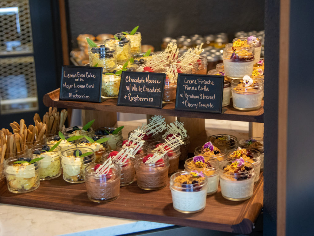 mason jars filled with small desserts and pickled vegetables on table