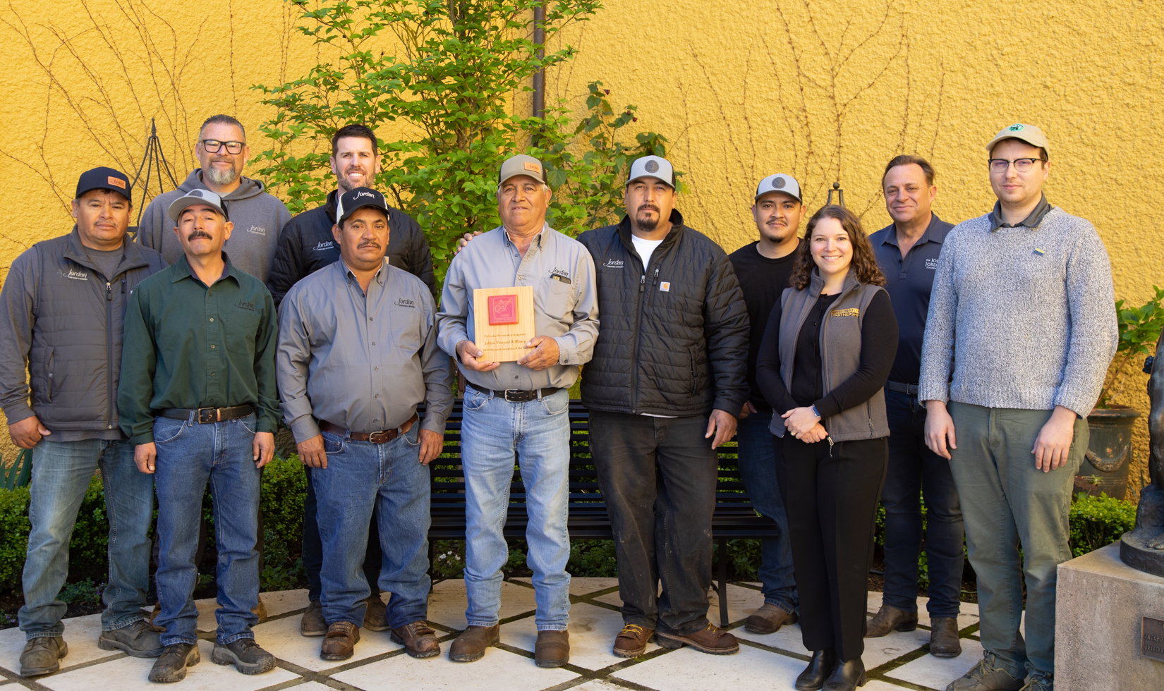 group of winery employees receiving sustainability award in courtyard