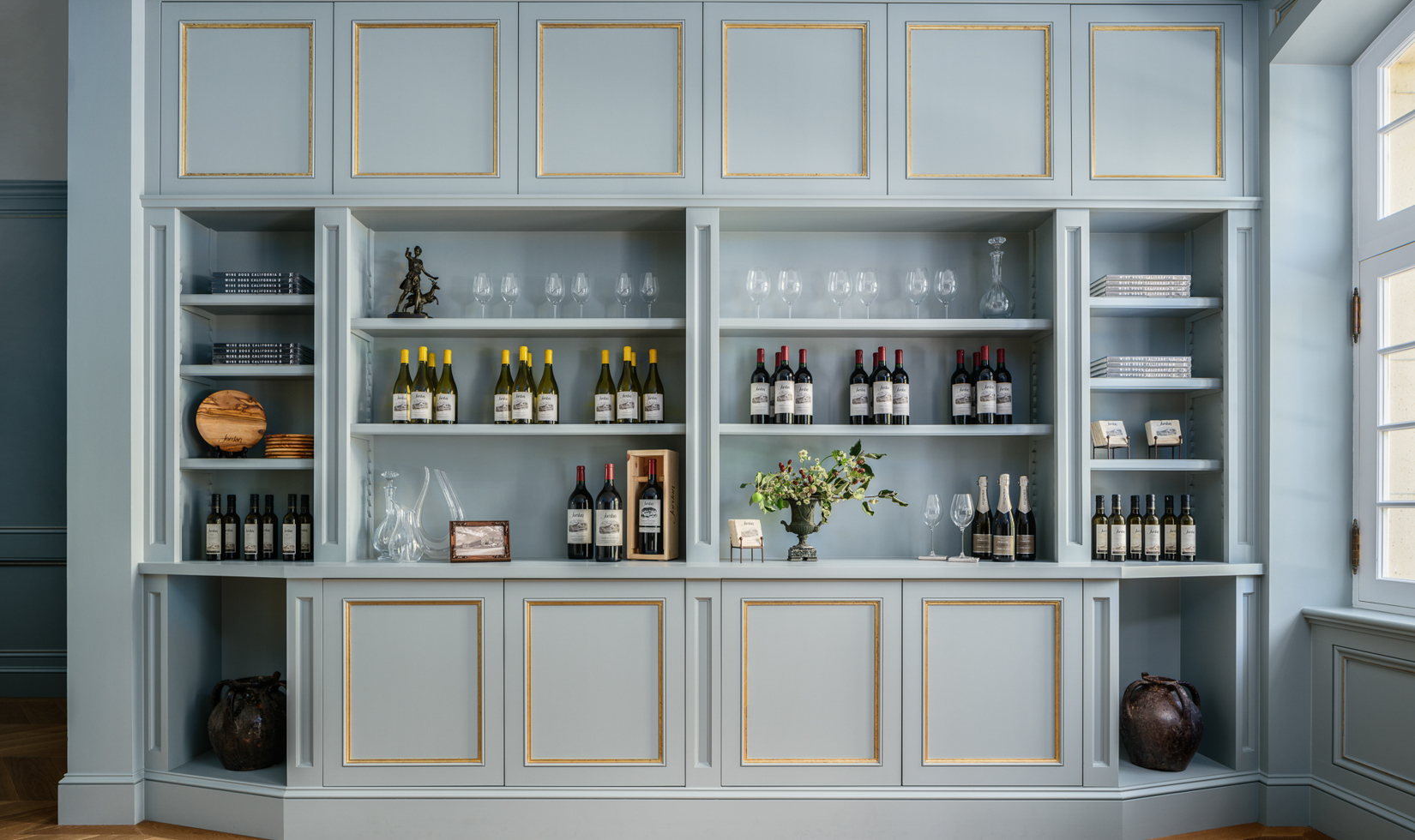 Retail display of wine bottles, decanters, olive oil and more on light blue shelving