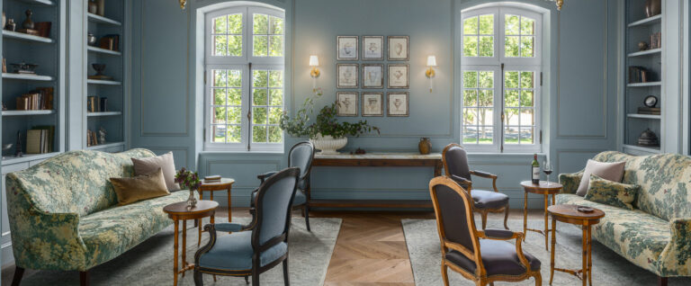 French-inspired living room with chandeliers and light blue walls, two sofas and sitting chairs