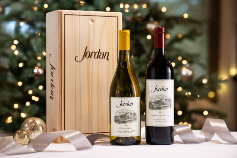 jordan wines and wooden gift box on table with silver ribbon and ornaments with christmas tree in background