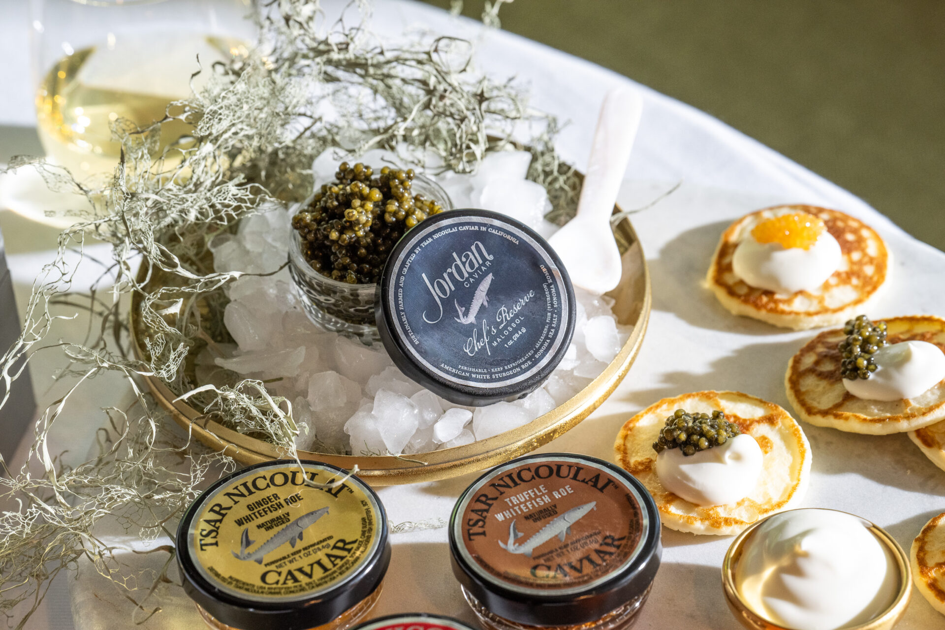 jordan's chef reserve caviar resting on top of dish of ice with blinis topped with crème fraiche and caviar on tray beside it