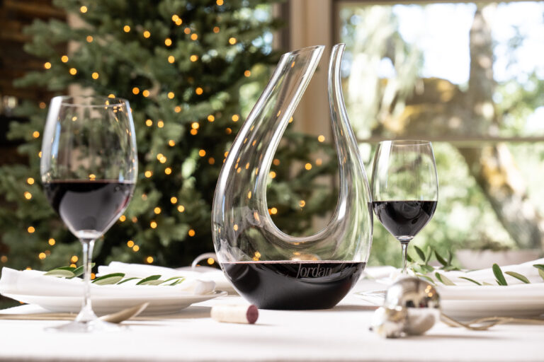 decanter in elegant rounded design filled with jordan cabernet sauvignon on table in front of christmas tree