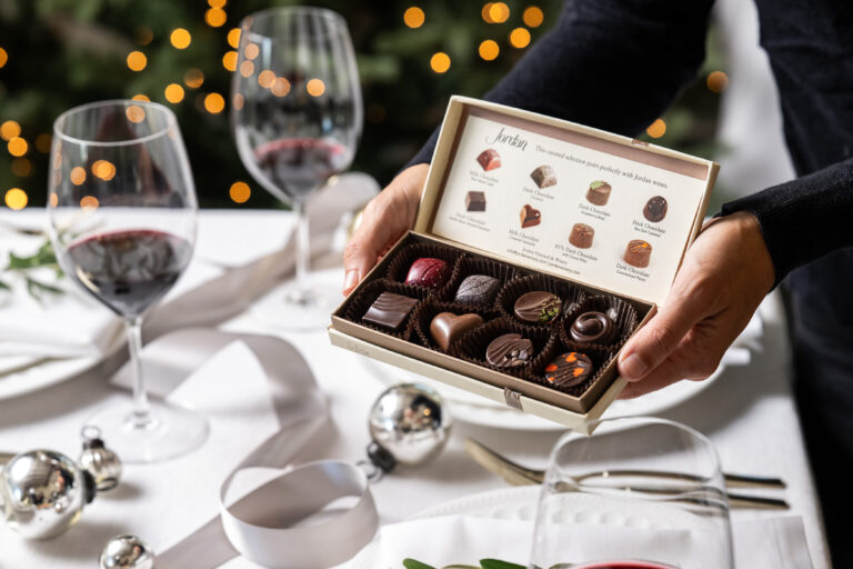 box of chocolate truffles held over table decorated for christmas