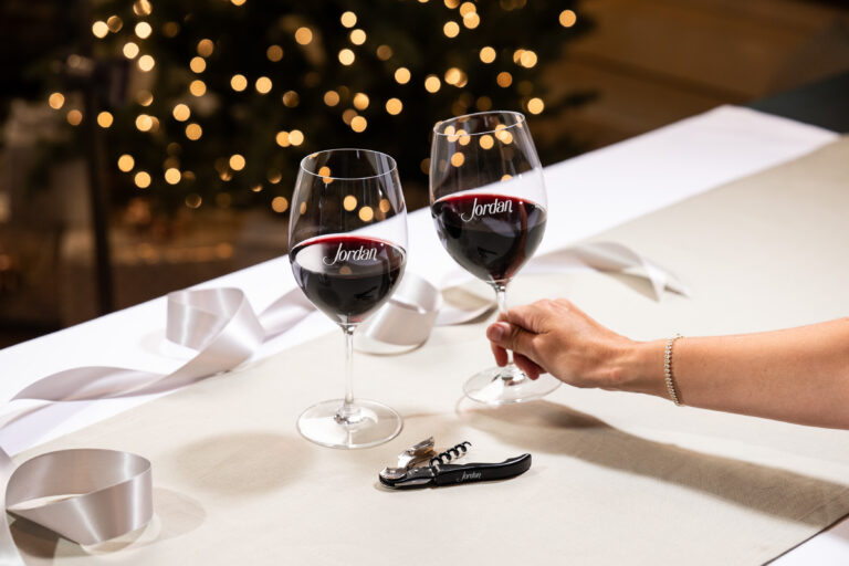 Riedel wine glasses with black Jordan corkscrew on table in front of Christmas tree