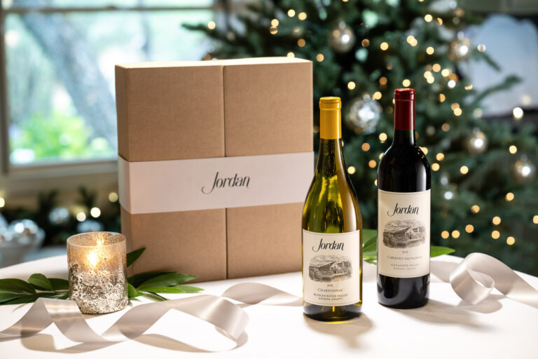jordan wines and wooden gift box on table with silver ribbon and candle with christmas tree in background