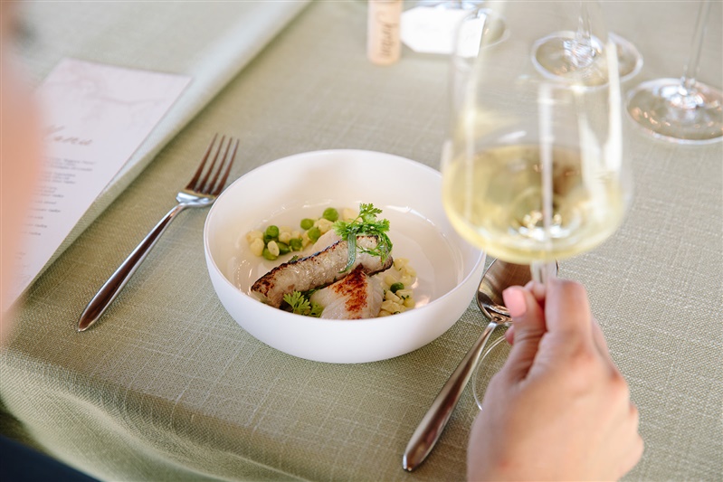 overhead shot of table setting with seafood dish on green table linen with a glass of chardonnay