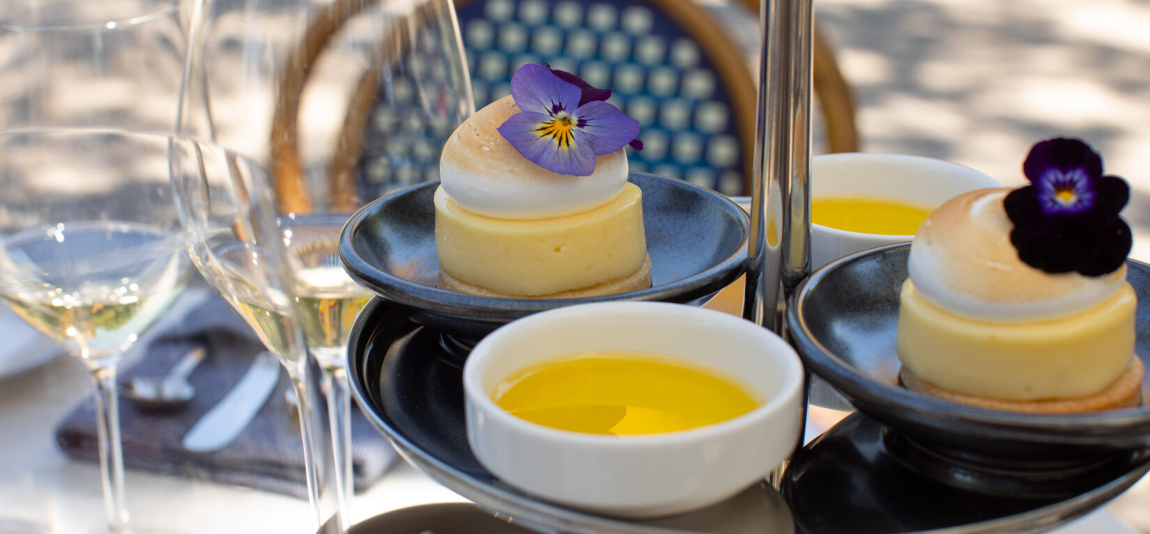 tiered silver tray on outdoor terrace table with dishes of olive oil and dessert tarts