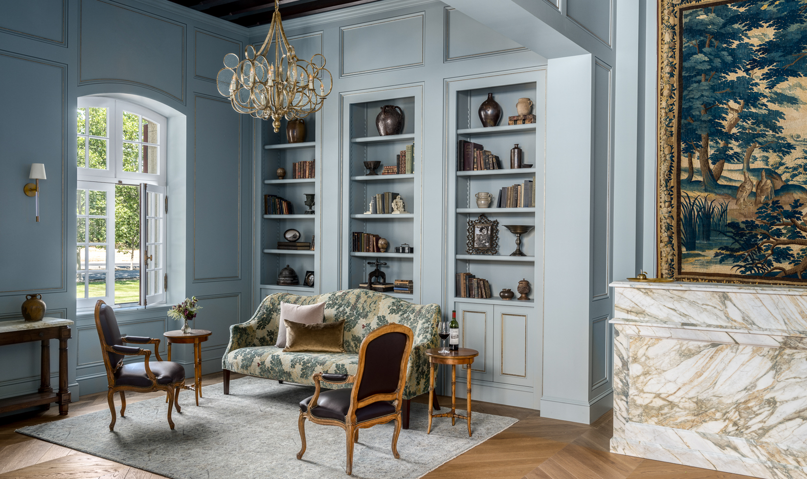 elegant winery lobby room with robin's blue wall panels, tapestry and sofa with shelves filled with decorative objects and antiques