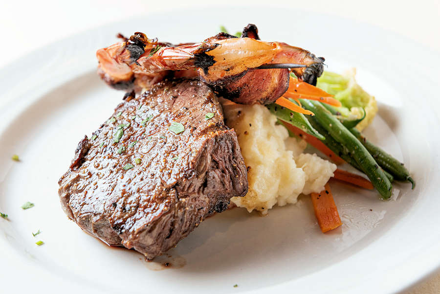 close-up photo of prime steak with mashed potatoes and roasted vegetables on white plate