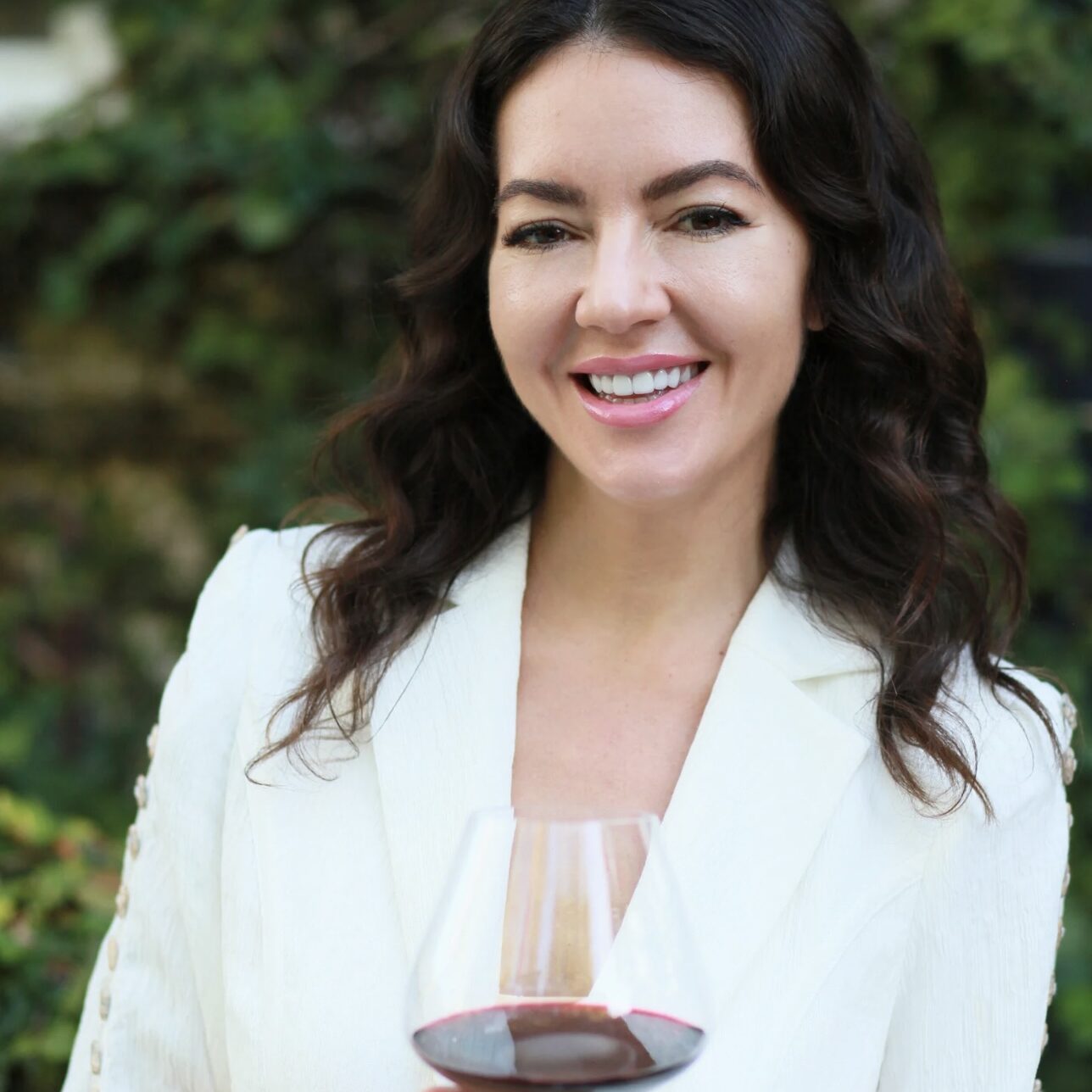 woman holding glass of red wine and smiling