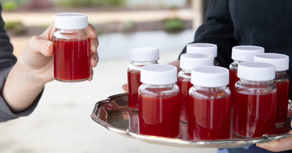 small wellness shots in glass jars served on silver tray