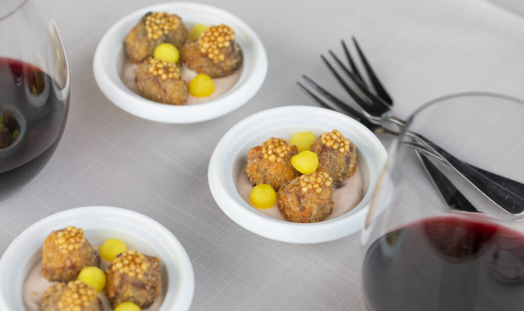 Crispy Short Ribs with Radish Soubise and Pickled Mustards Seeds & Daikon in small white bowls with glasses of red wine and forks on table