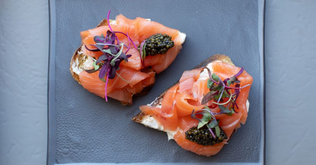overhead image of smoked salmon toast with caviar on blue plate
