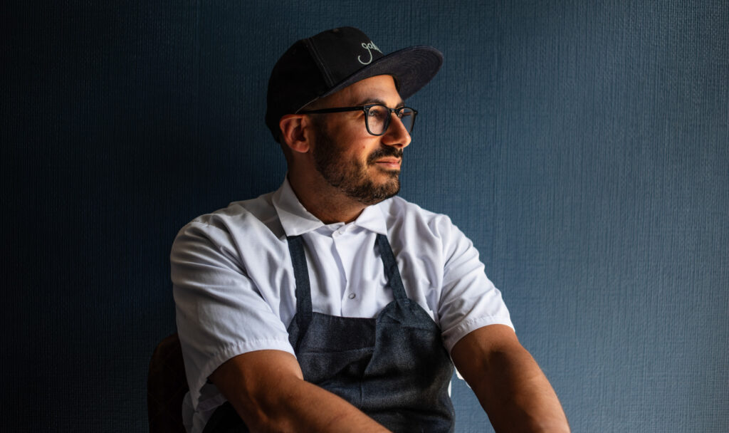 male chef sitting against charcoal wall