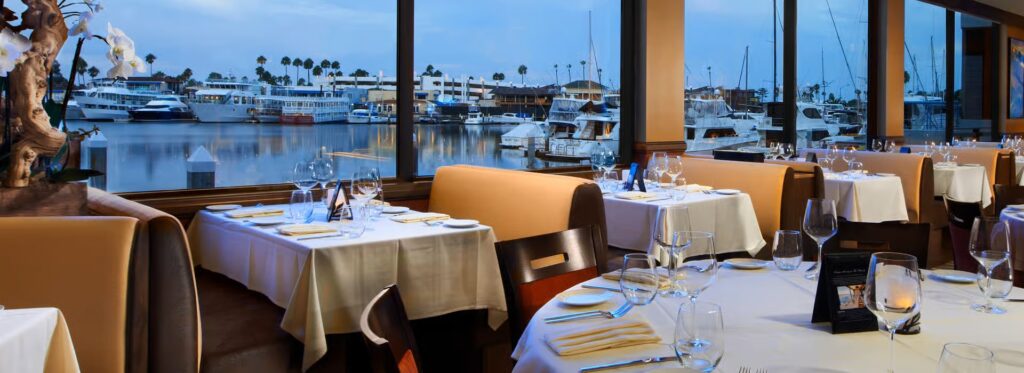 the dining room at the winery restaurant in newport beach with a view of a marina from the windows
