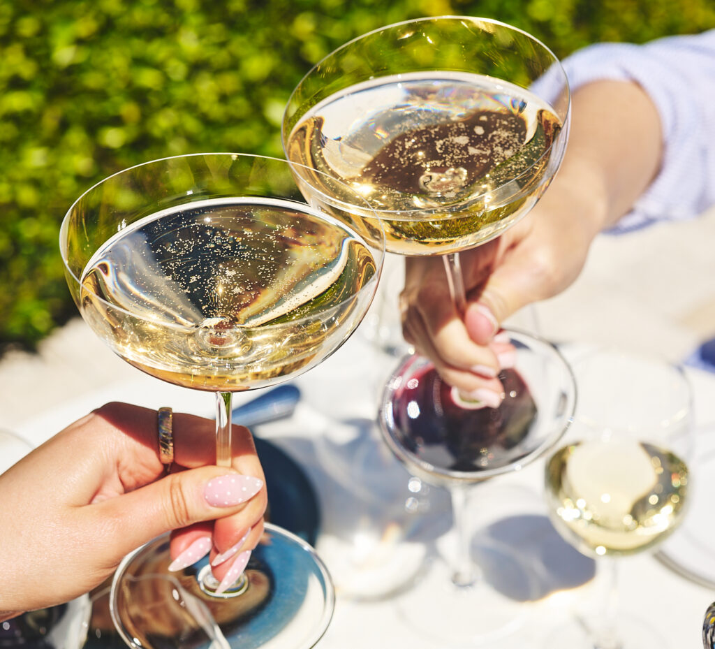 champagne glasses toasting outdoors over bistro table