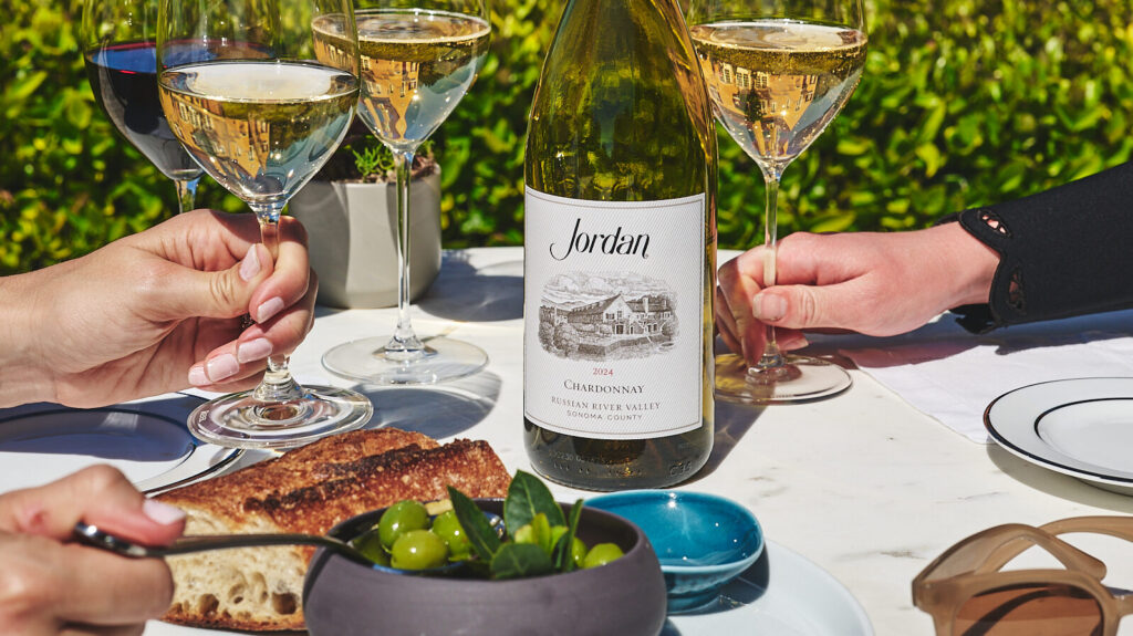 olives bread and olive oil on bistro table outdoors with chardonnay bottle and glasses
