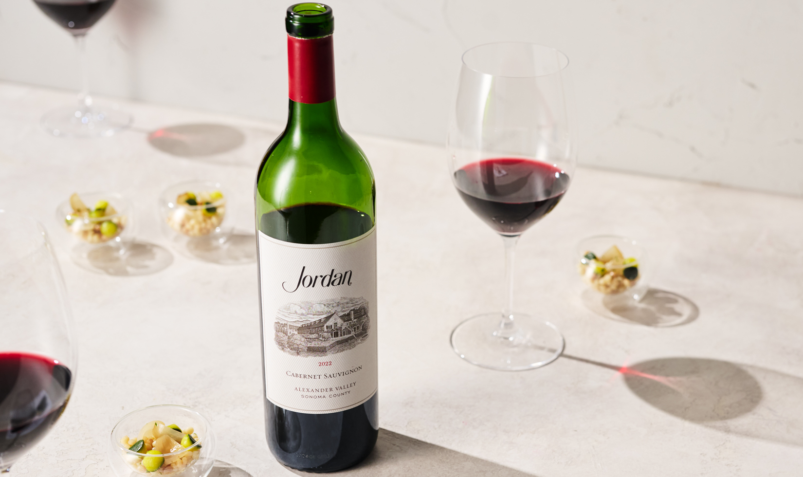 bottle of cabernet with small bites and glasses of red wine