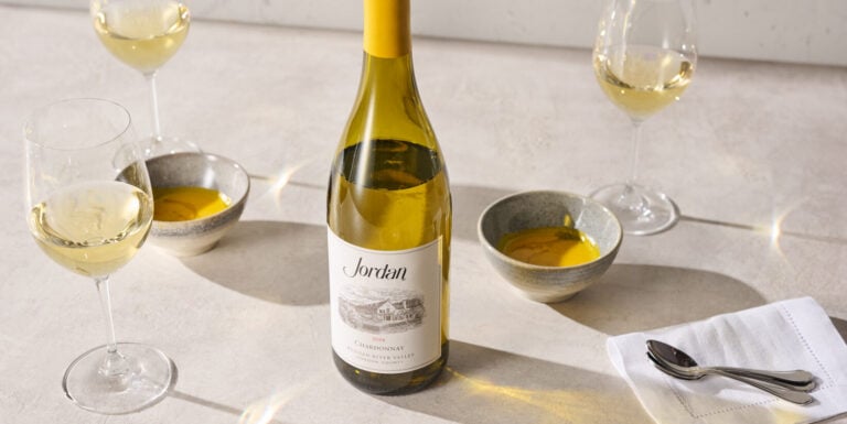 chardonnay bottle on table with small soups and glasses of white wine