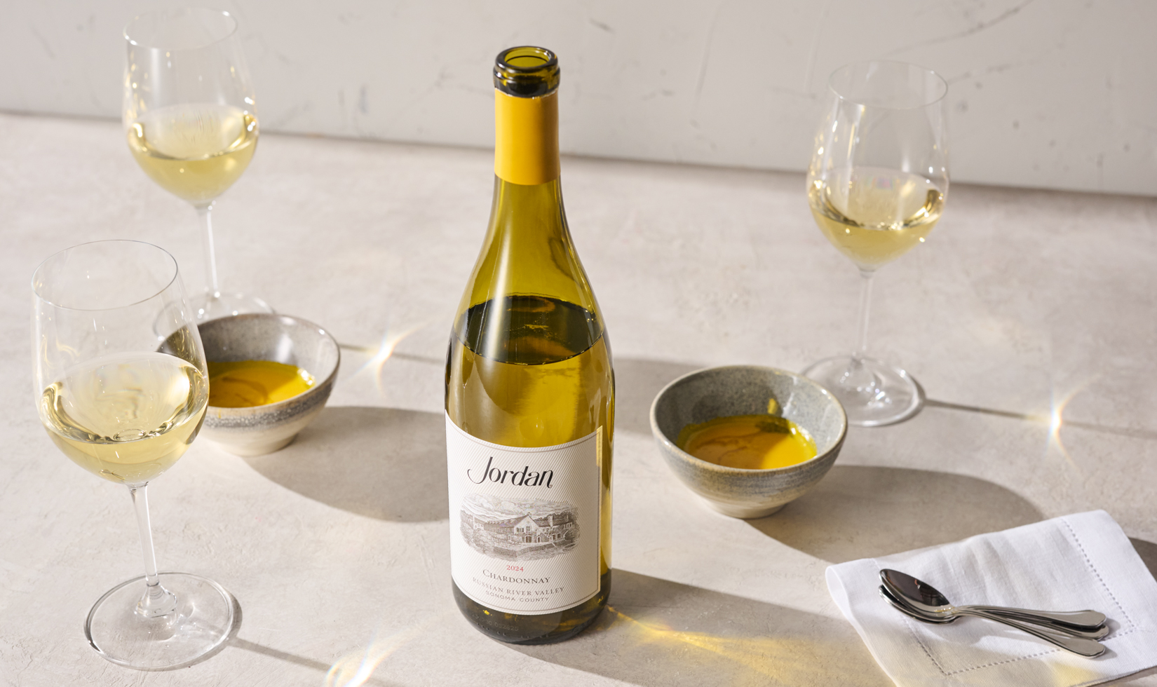 chardonnay bottle on table with small soups and glasses of white wine